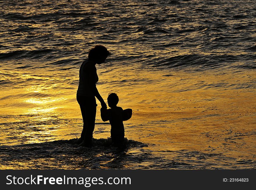 Mother and his son having good time on a beach at dusk. Mother and his son having good time on a beach at dusk.