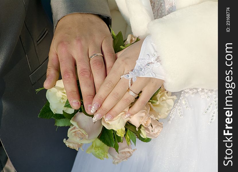 Hand of groom and fiancee on a background a bouquet from roses