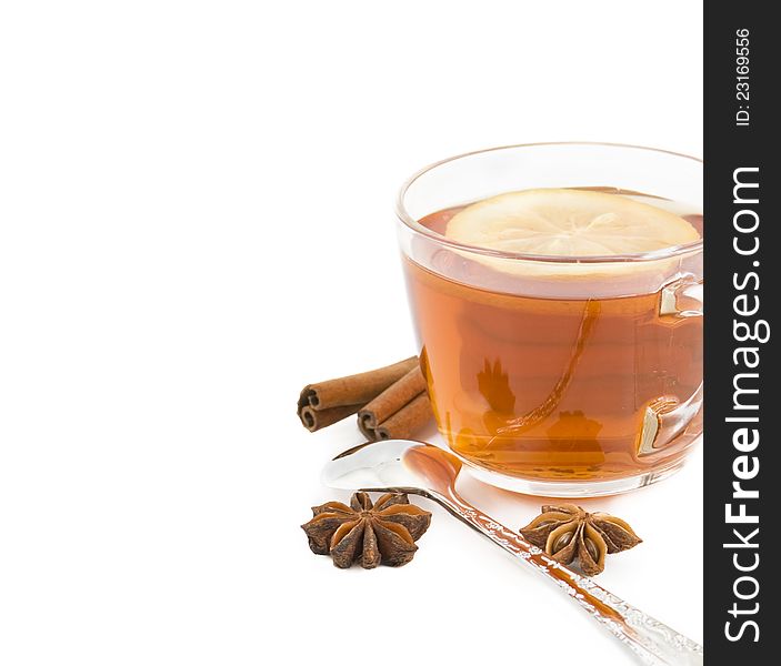 Cup of black tea with a lemon, cinnamon, anise and tea spoon on a white background