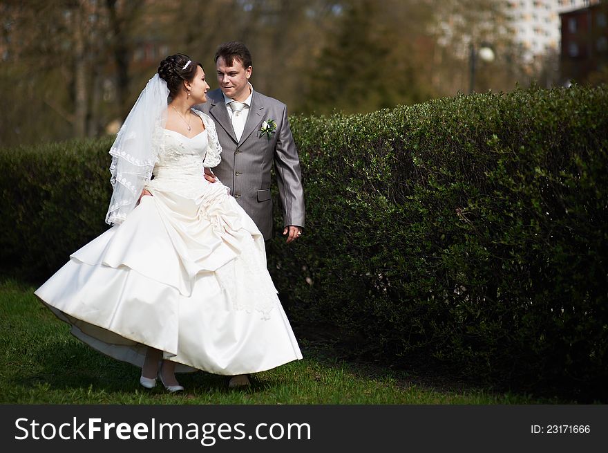Happy bride and groom walking in park