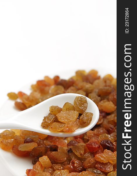 A handful of raisins in a white spoon on white background