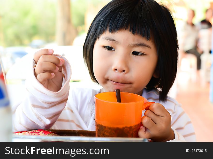 Little Asian Girl holding glass and enjoy her drink. Little Asian Girl holding glass and enjoy her drink