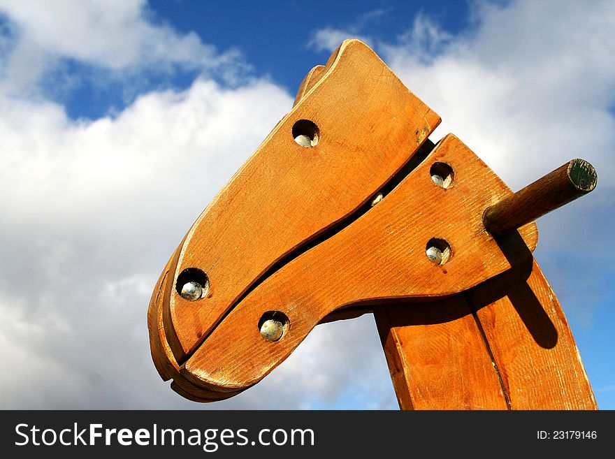Seesaw wooden horse head against cloudy skies