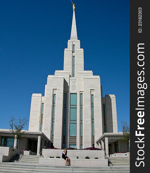 Image of the Oquirrh Mountain LDS Temple with a woman on the phone out front. Image of the Oquirrh Mountain LDS Temple with a woman on the phone out front