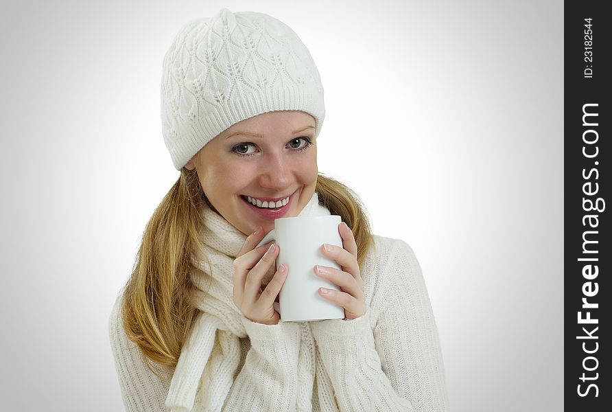 Beautiful happy young woman in a winter hat and scarf with a mug of hot drink. Beautiful happy young woman in a winter hat and scarf with a mug of hot drink