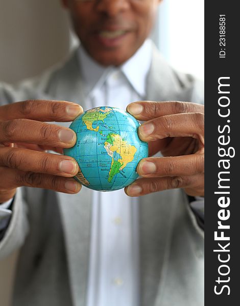 Image of a businessman squashing a globe in his hands
