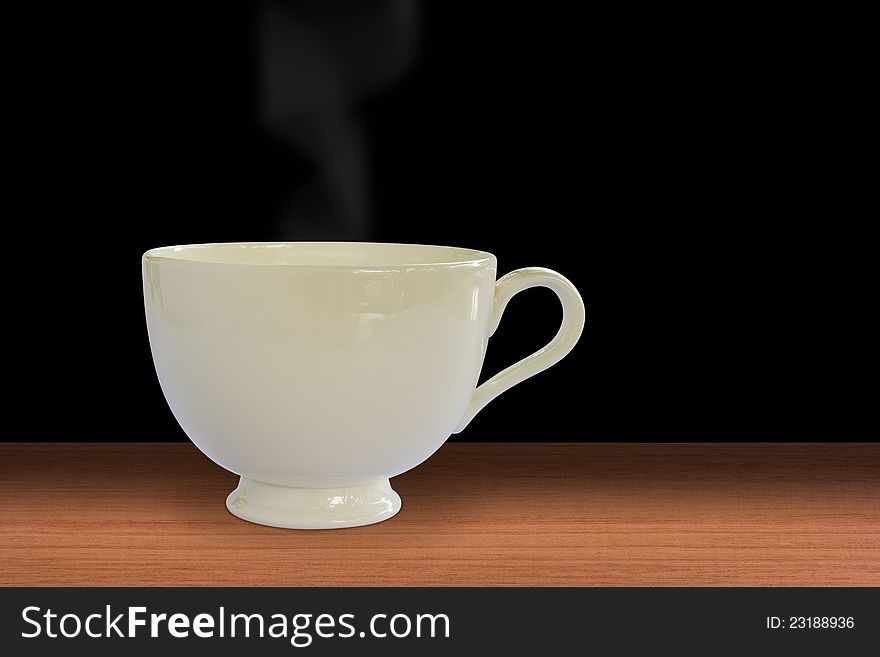 A cup of hot steaming coffee or tea on wooden table