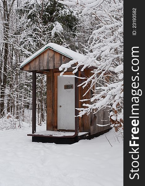 Rustic wooden outhouse in winter