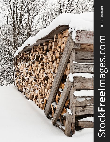 Neatly stacked pile of firewood in winter with fresh snow