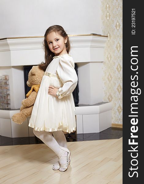 Smiling girl in white dress with toy bear