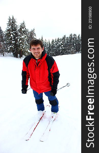 A smiling happy man skiing in a mountain forest