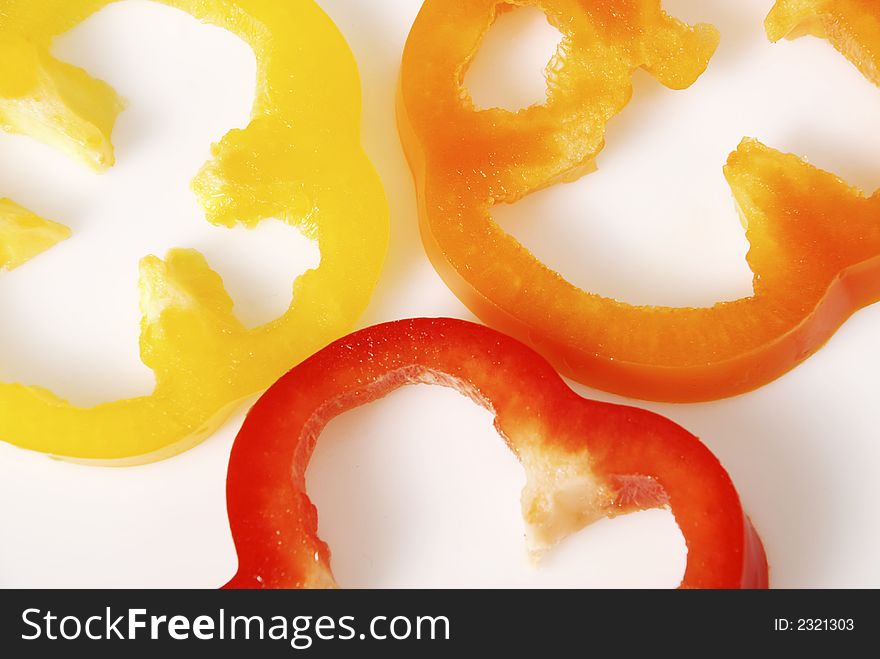 Red, orange and yellow peper slices isolated on white