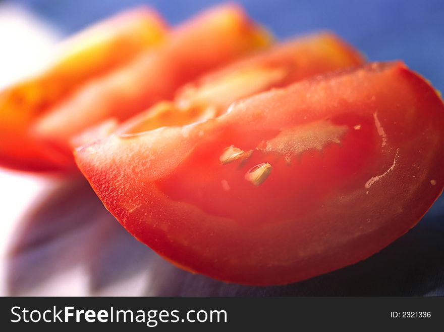 Slices of  cut red tomato on  dark blue background, close up. Slices of  cut red tomato on  dark blue background, close up