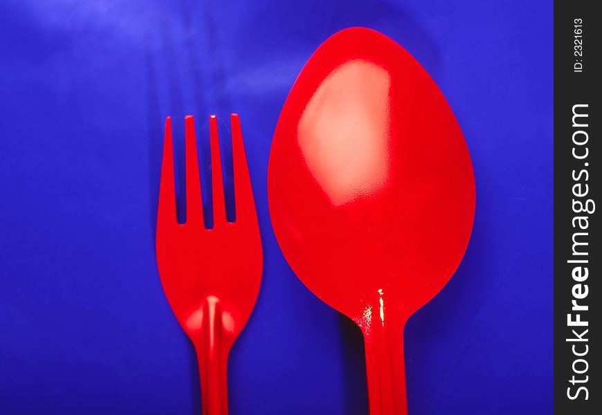 Brightly red spoon and plug on  dark blue background, close up. Brightly red spoon and plug on  dark blue background, close up