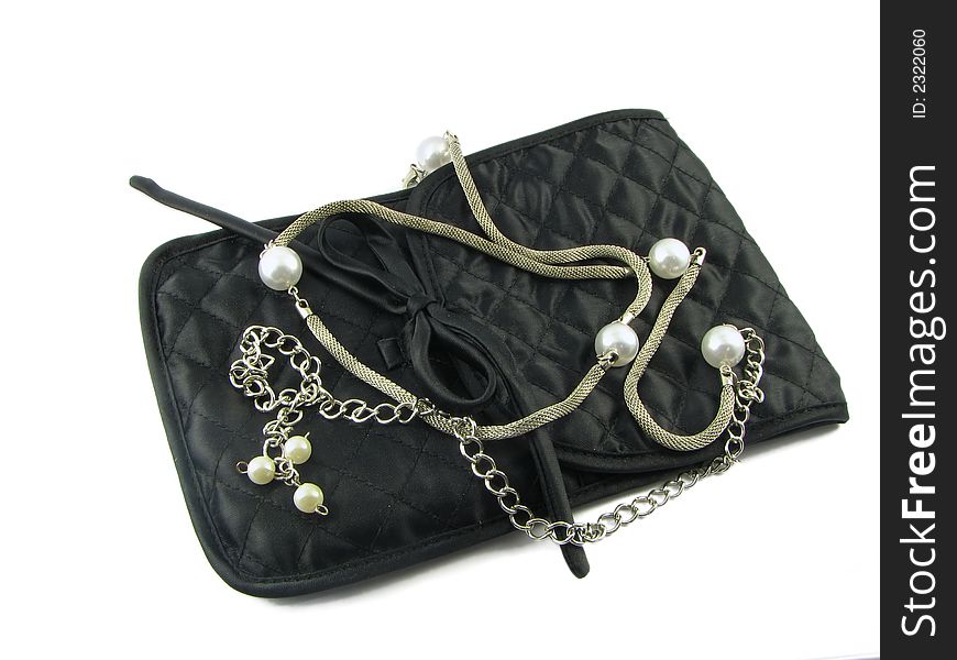 Silver beads with the pearls lie on the small, black bag. It is isolated against the white background. Silver beads with the pearls lie on the small, black bag. It is isolated against the white background.