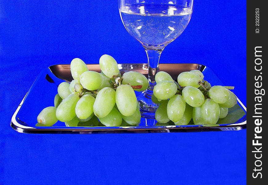 Cluster of green grapes and glass of wine in silver tray. Cluster of green grapes and glass of wine in silver tray