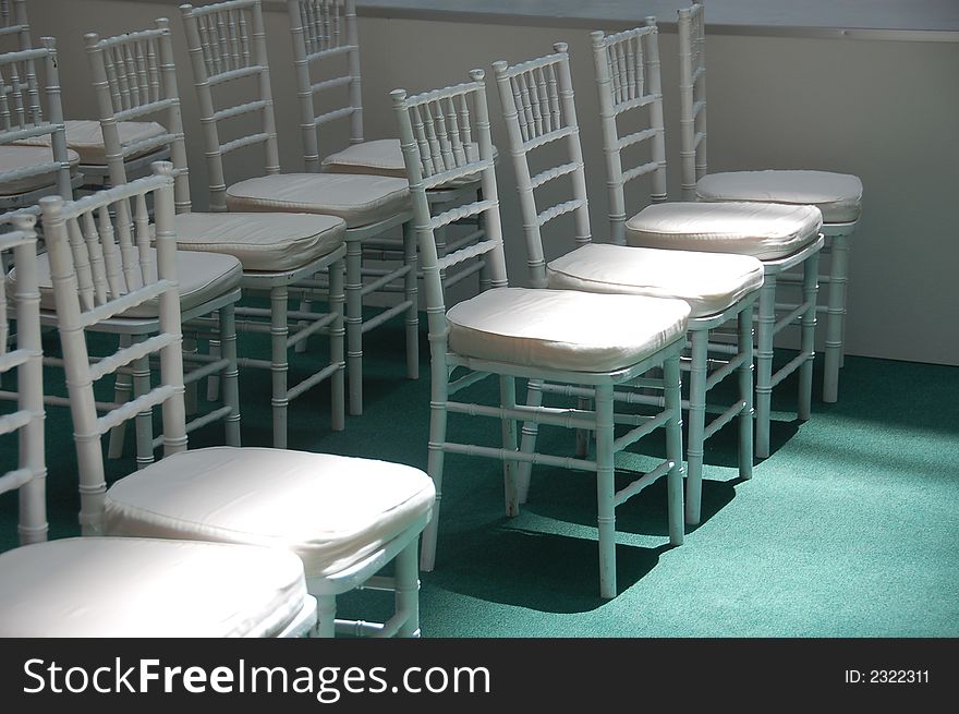 Rows of white chair with sun shining on front row. Rows of white chair with sun shining on front row