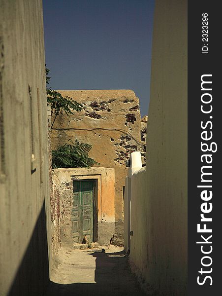 Greek passageway going down towards an old green door