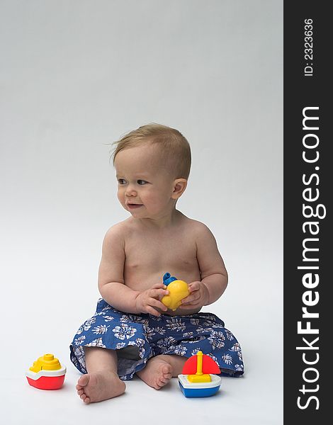 Image of an adorable baby wearing shorts, playing with toy boats. Image of an adorable baby wearing shorts, playing with toy boats