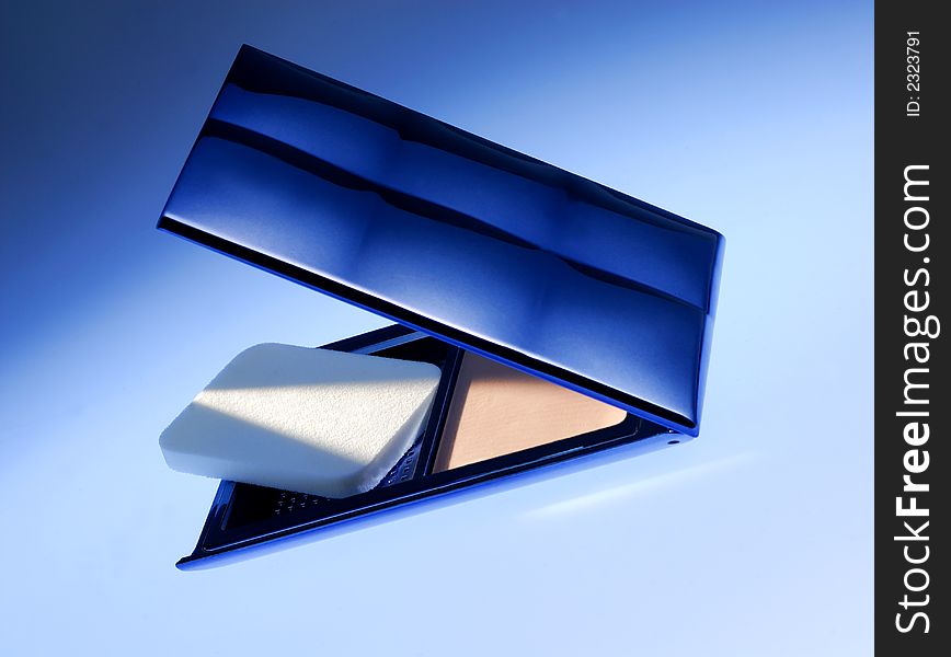 Cosmetic powder on blue background and in blue light. Cosmetic powder on blue background and in blue light