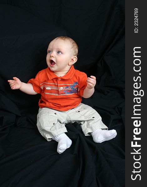 Cute little boy sitting in a black background