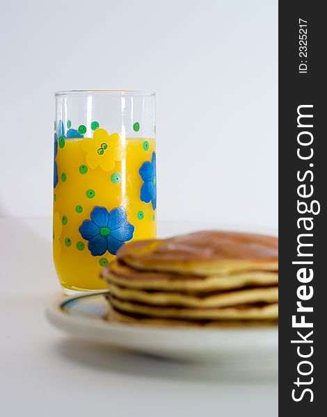 A stack of pancakes with a glass of orange juice. A stack of pancakes with a glass of orange juice