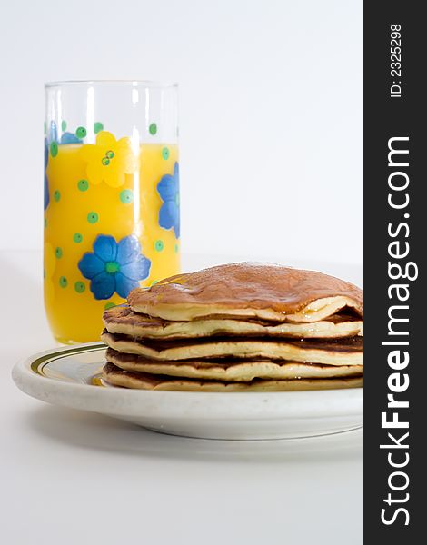 A stack of pancakes with a glass of orange juice. A stack of pancakes with a glass of orange juice