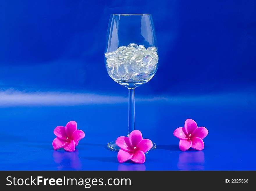 Wine glass with sparkling stones on a blue background. Wine glass with sparkling stones on a blue background