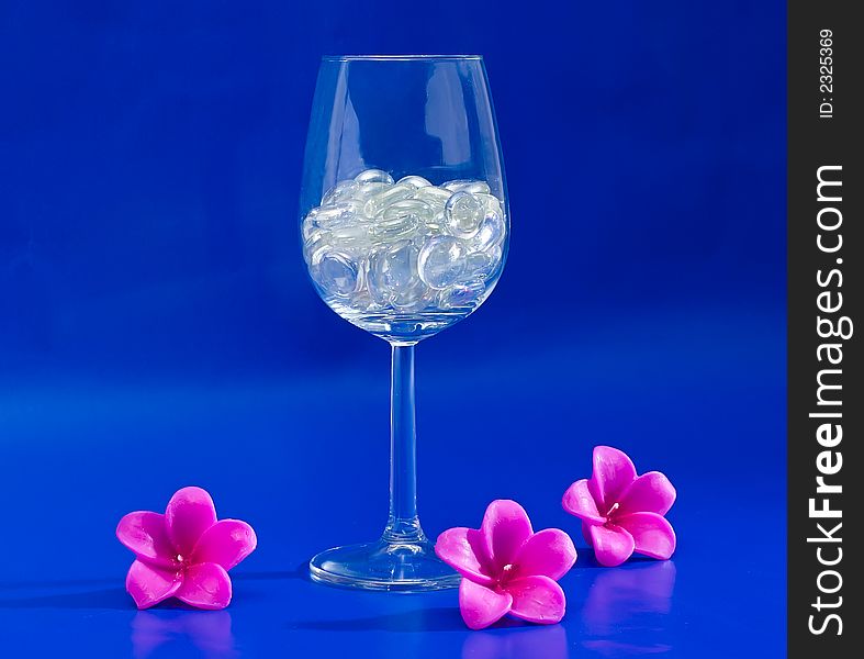 Wine glass with sparkling stones on a blue background. Wine glass with sparkling stones on a blue background