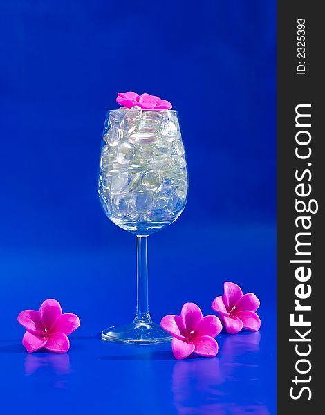 Wine glass with sparkling stones on a blue background. Wine glass with sparkling stones on a blue background