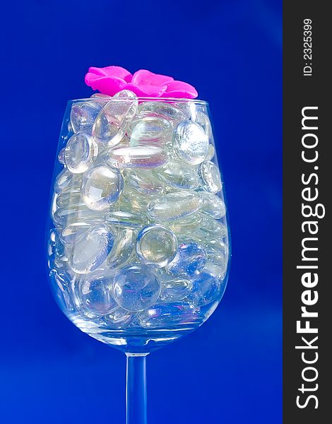 Wine glass with sparkling stones on a blue background. Wine glass with sparkling stones on a blue background