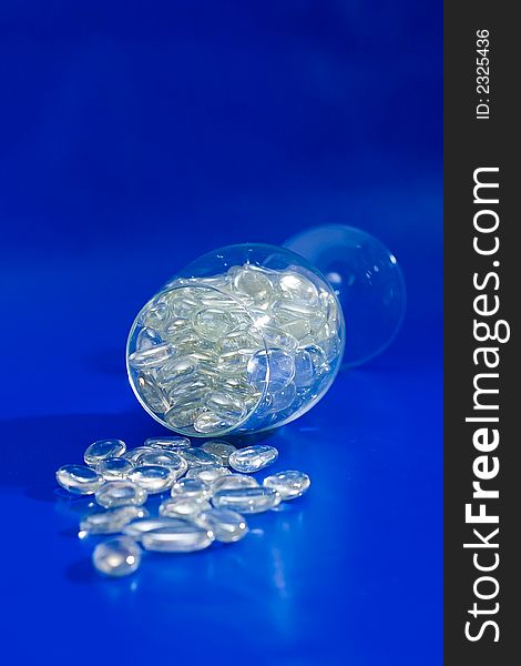 Wine glass with sparkling stones on a blue background. Wine glass with sparkling stones on a blue background