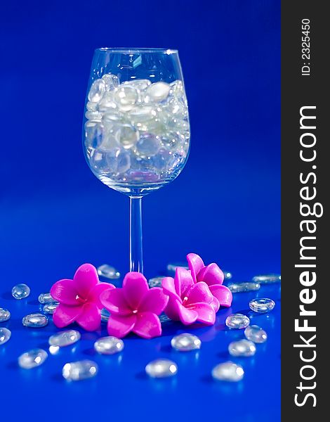 Wine glass with sparkling stones on a blue background. Wine glass with sparkling stones on a blue background