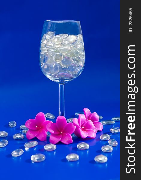 Wine glass with sparkling stones on a blue background. Wine glass with sparkling stones on a blue background