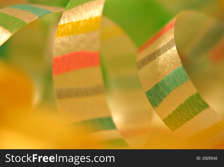 Close up of curls of striped ribbon on with a soft green and yellow background