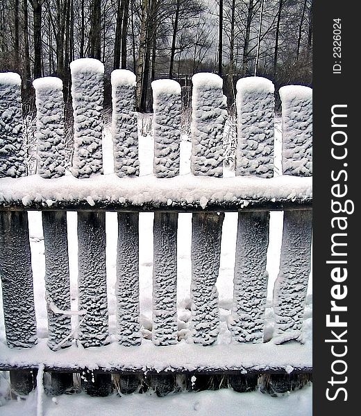 Wooden fence fallen asleep by white snow
