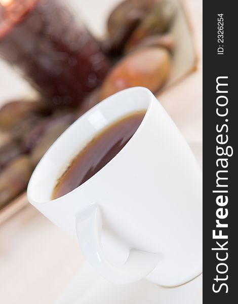 A cup of hot tea with stones and a candle in the background