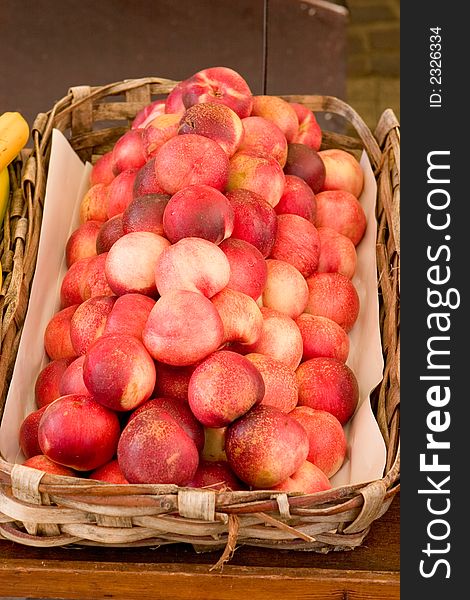 A basket full of fresh peaches at a market