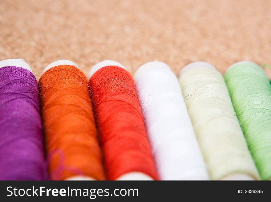 Six rolls of cotton on a cork background