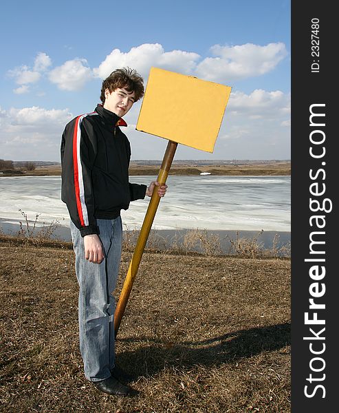 The young man with the tablet from metal costs on a background of a spring landscape. The young man with the tablet from metal costs on a background of a spring landscape.