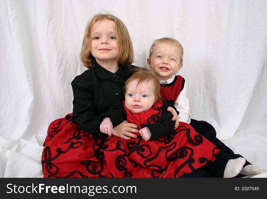 Three kids sitting together on a white background