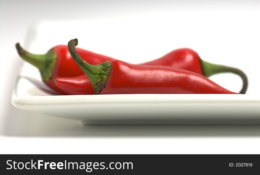 Three red peppers on white plate on white background. Three red peppers on white plate on white background