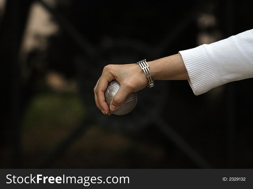 A tender hand holds with petanque ball. A tender hand holds with petanque ball