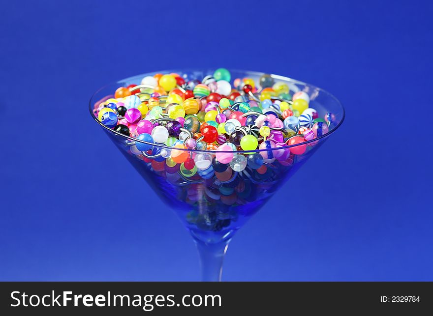 A martini glass full of navel rings. On Saturated Blue Background. A martini glass full of navel rings. On Saturated Blue Background