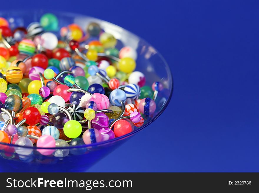 A martini glass full of navel rings. On Saturated Blue Background. A martini glass full of navel rings. On Saturated Blue Background