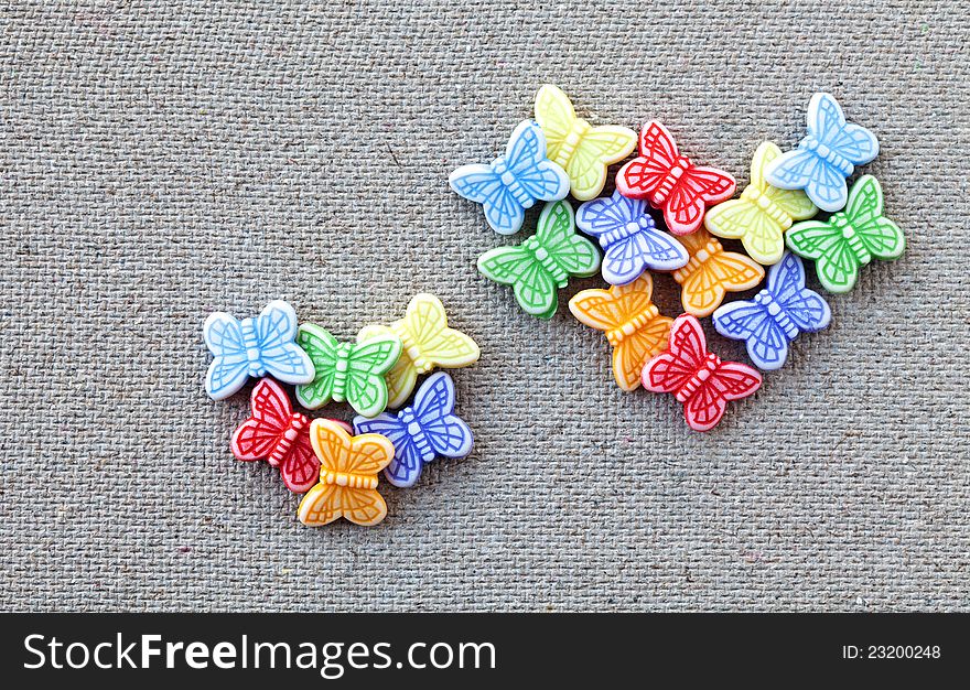 Two hearts made â€‹â€‹of plastic butterflies on a canvas background