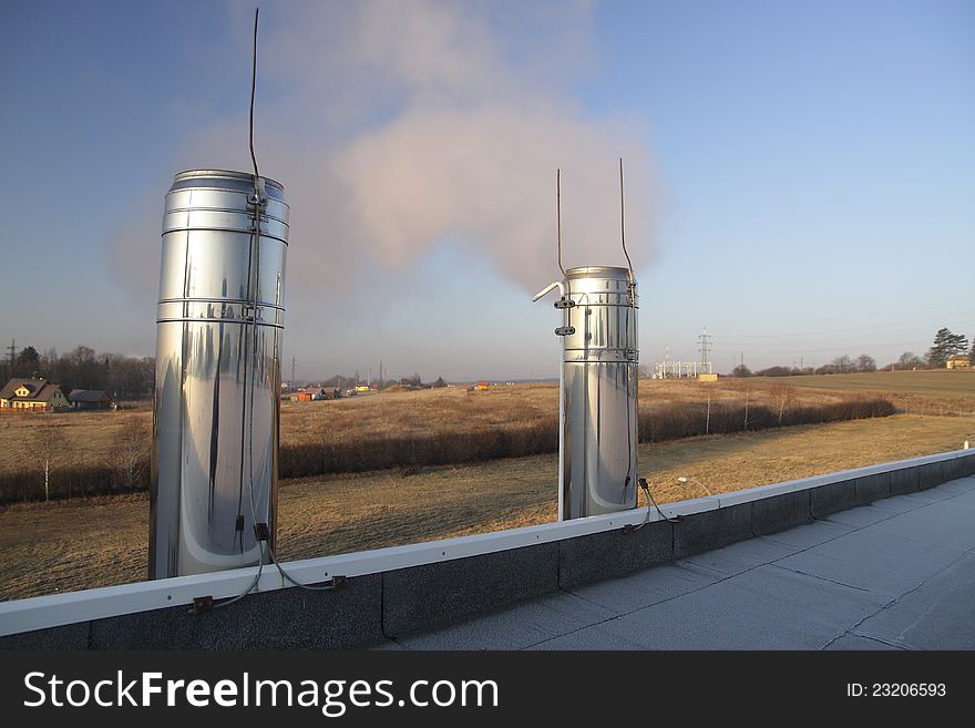 Two steaming chrome chimneys on the roof of a building