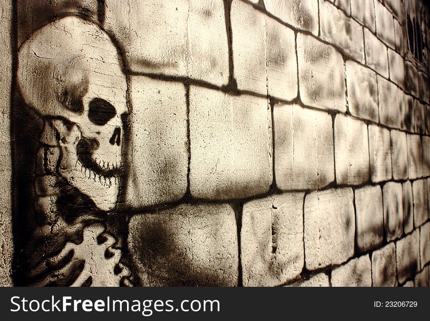 A skull painted on a wall with bricks indoor