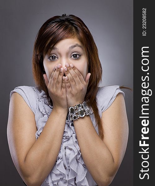 A latino woman puts her hand over her face in shock. A latino woman puts her hand over her face in shock