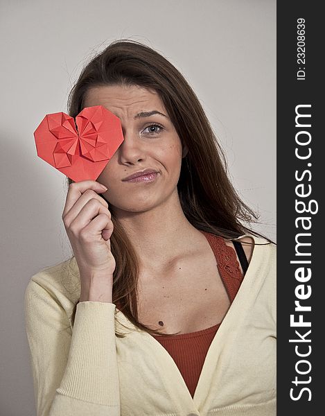 Young girl photographed on white background with origami Valentine heart made of paper